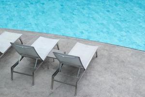 Chaises longues de piscine grises au bord de la piscine. photo