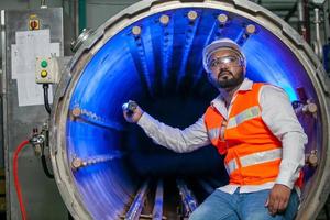 ingénieur technicien professionnel avec casque de sécurité travaillant à l'entretien des équipements de construction dans une usine industrielle, le travailleur vérifie ou répare la machine. photo