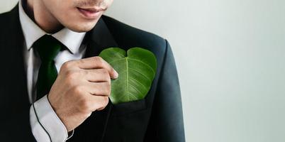 énergie verte, ressources renouvelables et durables. esg, concept de soins écologiques. gouvernance environnementale, sociale et d'entreprise. homme d'affaires insérer une feuille verte en forme de coeur dans la poche photo