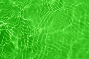 défocalisation floue transparente vert clair texture de surface de l'eau calme avec éclaboussures, bulle. fond d'ondulation de l'eau violet brillant. surface d'eau dans la piscine. éclat d'eau de bulle verte. photo