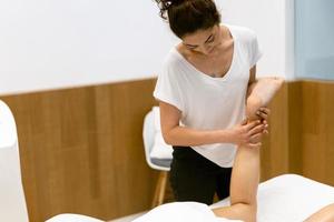 femme d'âge moyen ayant un massage des jambes dans un salon de beauté. photo