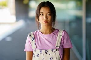 jeune femme chinoise regardant la caméra avec une expression sérieuse dans un immeuble de bureaux moderne photo