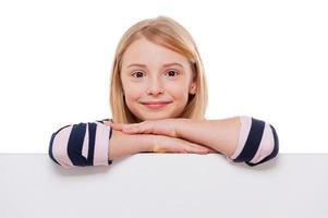 se penchant à l'espace de copie. joyeuse petite fille se penchant sur l'espace de copie et souriant tout en étant isolée sur blanc photo