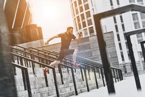 Pas de limites. toute la longueur du beau jeune homme en vêtements de sport sautant tout en faisant de l'exercice à l'extérieur photo