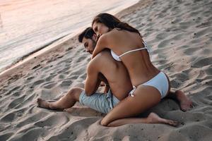 l'amour est tout ce qui compte. belle jeune femme embrassant son beau petit ami tout en se relaxant sur la plage photo