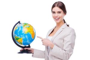 soutenir votre entreprise partout dans le monde. belles jeunes femmes tenant un globe et pointant dessus en se tenant debout sur fond blanc photo