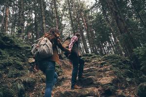 pas le temps de se détendre. vue arrière d'un jeune couple moderne se tenant la main et remontant lors d'une randonnée ensemble dans les bois photo