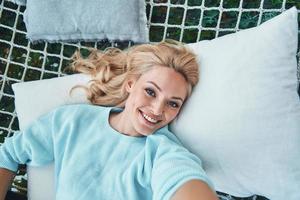 vue de dessus d'une belle jeune femme souriante faisant du selfie tout en se relaxant dans un grand hamac photo