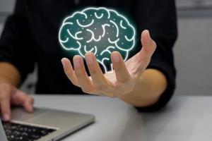 homme travaillant sur ordinateur portable avec illustration de cerveau de maintien. esprit artificiel et technologie future de développement. photo