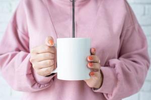 mains de femme en gros plan tenant une tasse blanche pour la conception de maquettes photo