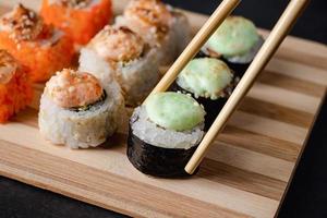 ensemble de rouleaux de sushi sur plateau de service en bambou. rouleau uramaki, baguettes et sauce soja. photo