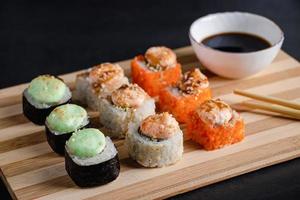ensemble de rouleaux de sushi sur plateau de service en bambou. rouleau uramaki, baguettes et sauce soja. photo
