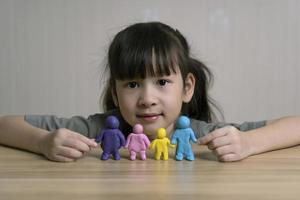 jolie fille asiatique construit une figurine en pâte à modeler de maman, papa et enfant et frère. concept de maison familiale et relations familiales. la chaleur et l'amour de la famille. la créativité et l'apprentissage des enfants photo