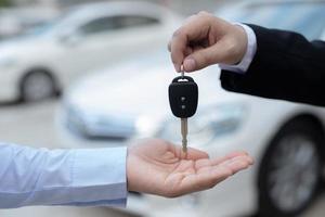 le vendeur porte les clés de voiture livrées au client dans la salle d'exposition avec une offre à faible intérêt. promotion spéciale photo