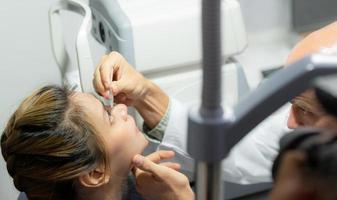 un ophtalmologiste met des larmes artificielles dans les yeux de la fille. photo