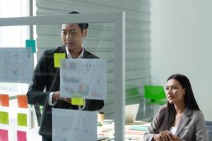 de jeunes entrepreneurs en asie organisent des réunions pour réfléchir et examiner les informations sur le tableau de verre photo