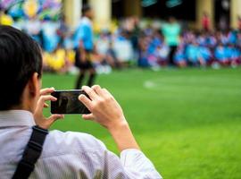 homme en uniforme de travail regarder et tirer des compétitions de football à côté d'un terrain de football photo