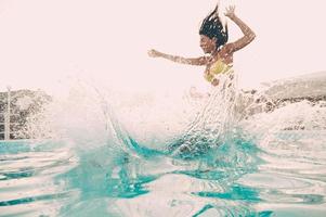 plaisir de la piscine. belle jeune femme sautant dans la piscine extérieure photo