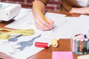 créer un nouveau look de mode. gros plan d'une femme dessinant un croquis de mode assis sur son lieu de travail photo