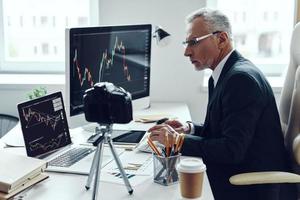 homme senior en costume d'affaires élégant utilisant des technologies modernes tout en réalisant une vidéo sur les réseaux sociaux photo