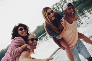 plaisir déchaîné. de beaux jeunes couples passent du temps sans soucis en se tenant debout sur la jetée photo