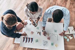 réflexion. vue de dessus en gros plan de jeunes gens d'affaires confiants travaillant ensemble pendant qu'un homme écrit sur un plan au bureau photo