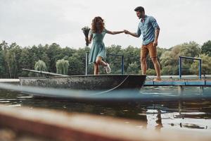 totalement amoureux. heureux jeune couple se prépare à ramer un bateau tout en profitant de leur rendez-vous à l'extérieur photo