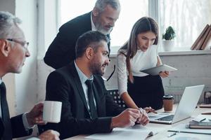 collègues concentrés planifiant la prochaine étape commerciale tout en travaillant ensemble dans le bureau moderne photo