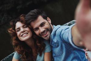 capturer des moments heureux. autoportrait d'un beau jeune couple regardant la caméra assis dans le bateau à l'extérieur photo