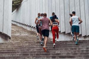 vue arrière pleine longueur de personnes en vêtements de sport faisant du jogging tout en faisant de l'exercice sur les marches à l'extérieur photo