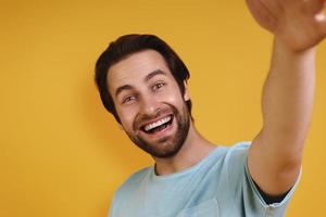 portrait d'un jeune homme heureux en vêtements décontractés faisant selfie et souriant photo