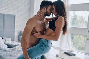 la passion. beau jeune homme torse nu portant une femme séduisante semi-habillée debout dans la chambre photo