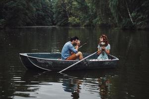 joli tir. jeune homme photographiant sa belle petite amie tout en profitant d'un rendez-vous romantique sur le lac photo