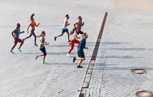 vue de dessus sur toute la longueur des jeunes en vêtements de sport faisant du jogging tout en faisant de l'exercice à l'extérieur photo