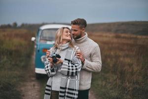 heureux d'être autour. beau jeune couple embrassant et souriant tout en se tenant à l'extérieur photo