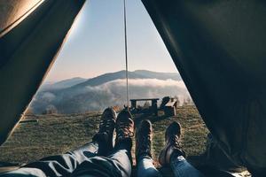d'abord qu'ils voient le matin. gros plan d'un jeune couple profitant de la vue sur la chaîne de montagnes en position couchée dans leur tente photo