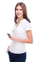 beauté avec téléphone portable. belles jeunes femmes tenant un téléphone portable et souriant en se tenant debout sur fond blanc photo