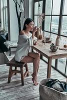 repas du matin. jolie jeune femme mangeant un petit-déjeuner sain et regardant loin avec le sourire tout en étant assise près de la fenêtre à la maison photo