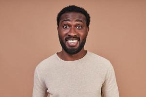 portrait d'un beau jeune homme africain en vêtements décontractés faisant une grimace et regardant la caméra photo