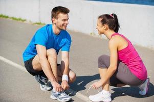 se préparer pour le jogging. vue de dessus d'un jeune homme et d'une femme attachant des lacets et se regardant tout en étant à l'extérieur photo