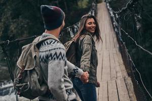 couple romantique. beau jeune couple main dans la main en marchant sur le pont suspendu photo