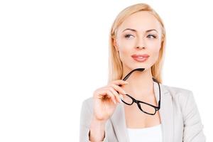 réfléchir à de nouvelles opportunités. femme d'affaires mûre réfléchie tenant des lunettes et regardant loin en se tenant debout sur fond blanc photo