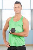 gars de remise en forme. jeune bel homme en chemise verte soulève des poids photo