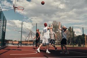 tir au but. groupe de jeunes hommes en vêtements de sport jouant au basket tout en passant du temps à l'extérieur photo