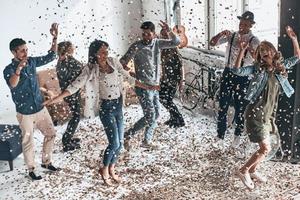 laissez tous les soucis derrière la vue de dessus pleine longueur de jeunes gens heureux gesticulant et souriant tout en dansant avec des confettis volant partout photo