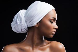alliant beauté et tradition. belle femme africaine portant un foulard et gardant les yeux fermés en se tenant debout sur fond noir photo