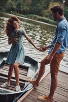un rendez-vous romantique. heureux jeune couple se prépare à ramer un bateau tout en profitant de leur rendez-vous à l'extérieur photo