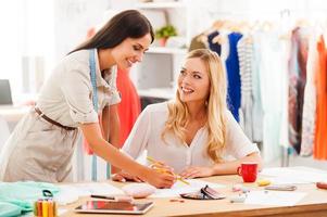 l'inspiration vient plus vite quand nous sommes ensemble. deux jeunes femmes gaies travaillant ensemble dans leur atelier de mode photo