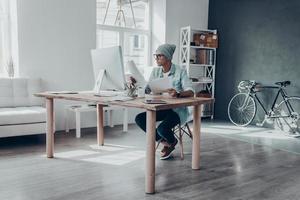 analyser les données. sérieux jeune homme moderne travaillant avec des documents tout en étant assis sur son lieu de travail dans un bureau de création photo