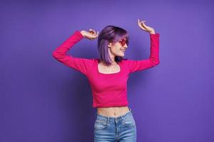 joyeuse jeune femme dansant en se tenant debout sur fond violet photo